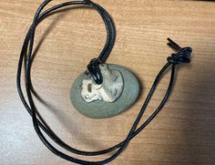 This stone was recovered from Lake Erie and made into a necklace with metal and leather.  It was sold by a gallery in Cleveland's Little Italy. The metal is etched with various symbols. The stone is smooth. The stone is approximately 1.5 x 1.25 inches, and the leather is about 12 inches long. Adjustable Symbolic Stamped Necklace, Symbolic Etched Adjustable Necklace, Adjustable Etched Symbolic Necklace, Adjustable Metal Engraved Necklace, Adjustable Engraved Metal Necklace, Adjustable Hand Forged Round Pendant Necklace, Symbolic Adjustable Etched Necklace, Symbolic Adjustable Etched Necklaces, Adjustable Symbolic Etched Necklace