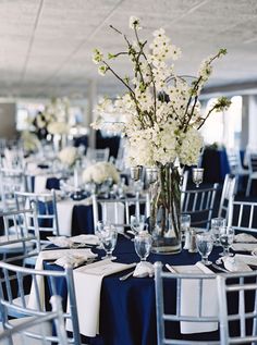 a vase filled with white flowers sitting on top of a table covered in blue cloths