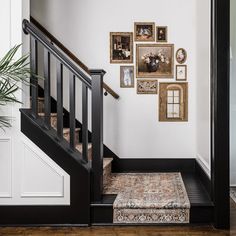 a staircase with pictures on the wall next to it and a rug under the stairs