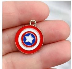 the captain's shield charm is being held up in someone's hand,