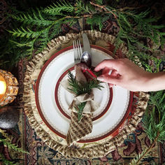 a person holding a knife and fork on top of a plate next to a candle