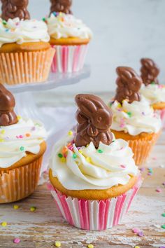 some cupcakes with white frosting and chocolate bunny ears on top are sitting on a table