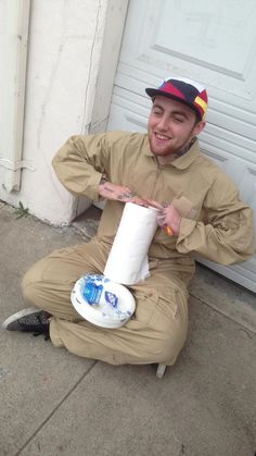 a man sitting on the ground holding a roll of toilet paper