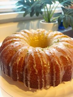 a bundt cake sitting on top of a white plate next to a potted plant