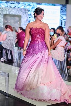 a woman in a pink and purple dress walking down the runway