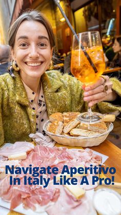 a woman sitting at a table with food and wine in front of her, smiling for the camera