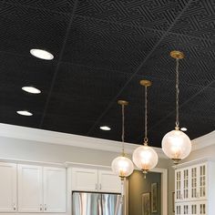 a kitchen with white cabinets and lights hanging from it's black tint ceiling