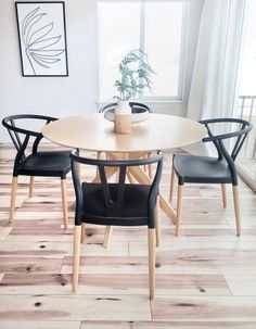 a dining room table with four chairs and a vase on the table in front of it