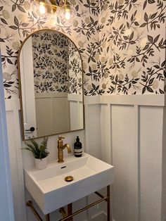 a white sink sitting under a bathroom mirror next to a wall mounted faucet