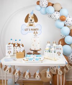 a dog themed birthday party with balloons, cake and desserts on a white table