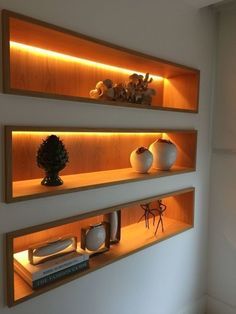 three shelves with vases, books and other items on them are lit up at night