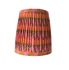 a pink and yellow lamp shade with pineapples printed on it's sides