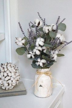 a vase filled with cotton sitting on top of a white table next to a plant