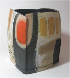 a ceramic vase with an abstract design on it's side, sitting on a white surface