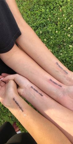 three people sitting on the ground with their feet crossed and one has writing on them