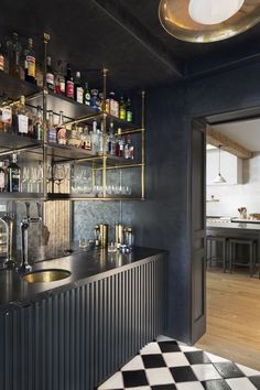 a bar with lots of liquor bottles on the shelves and checkered flooring in front of it