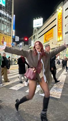 a woman in short shorts and knee high boots is dancing on the street