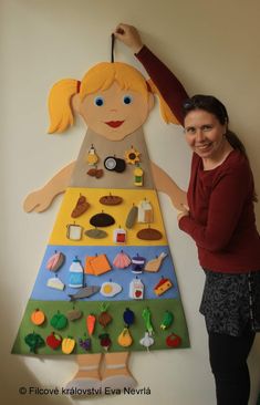 a woman standing next to a large paper cut out of a child's food pyramid