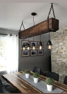 a dining room table and chairs with lights hanging from the ceiling above it, along with pictures on the wall