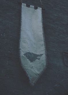 a white banner with a black bird on it hanging from a hook in the wall