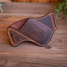 a brown leather case with stitching on the inside of it sitting on a wooden table