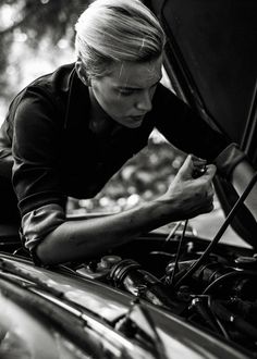 a woman working on the hood of a car