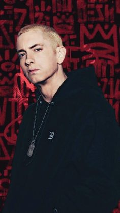 a young man with blonde hair and piercings standing in front of a red background