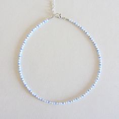 a white and blue beaded necklace on a silver chain