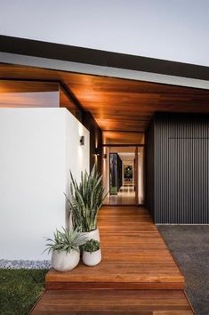 a house with wooden steps leading up to the front door and side entrance, along with two large planters on either side of the entryway