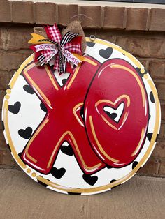 a red and white sign with the letter k painted on it's side next to a brick wall