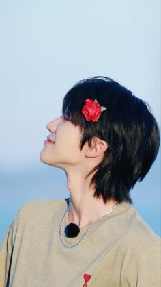 a woman with a flower in her hair looking off into the distance, against a blue sky