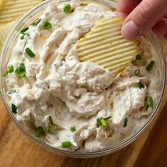 a person dipping a potato chip into a bowl of dip