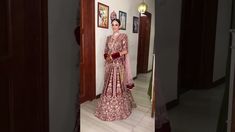 a woman in a pink and gold bridal gown standing in front of a doorway