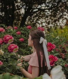 a girl in a pink dress standing among flowers