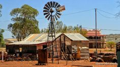 an old wooden building with a windmill in the middle of it and cars parked outside