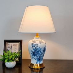 a blue and white vase sitting on top of a wooden table next to a lamp