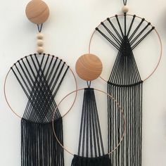 three black and white wall hangings with wooden circles on the top, one in the middle