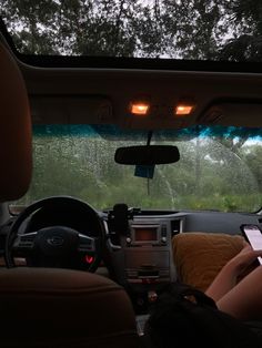 a person sitting in the back seat of a car using a cell phone while driving