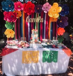 a table topped with lots of colorful paper flowers next to a sign that says canka