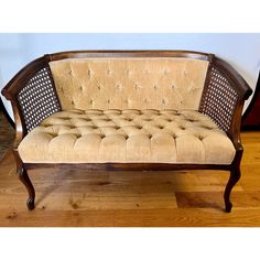 an old wooden bench with beige upholstered fabric and wood trimmings on it