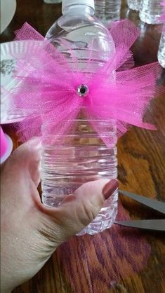 a person holding a bottle with pink ribbon on it