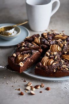 a chocolate cake with nuts on top next to a cup and saucer