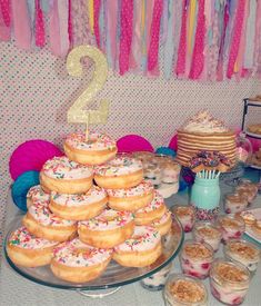 a table topped with lots of donuts covered in frosting and sprinkles