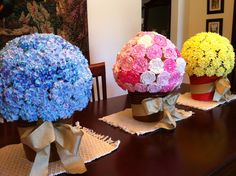 three vases filled with flowers sitting on top of a wooden table