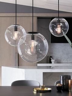 three clear glass globes hang from the ceiling above a dining room table and chairs