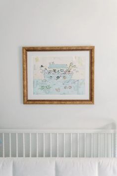 a white crib with a painting hanging above it