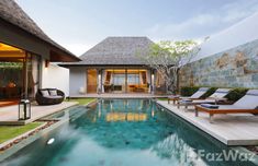 an outdoor swimming pool with chaise lounges next to it and a stone wall