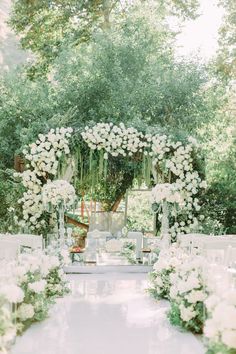 an outdoor ceremony with white flowers and greenery