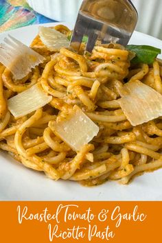 a plate of pasta with cheese and basil on top, next to a fork in the middle