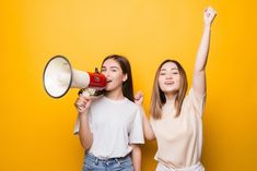 two young women standing next to each other holding a megaphone